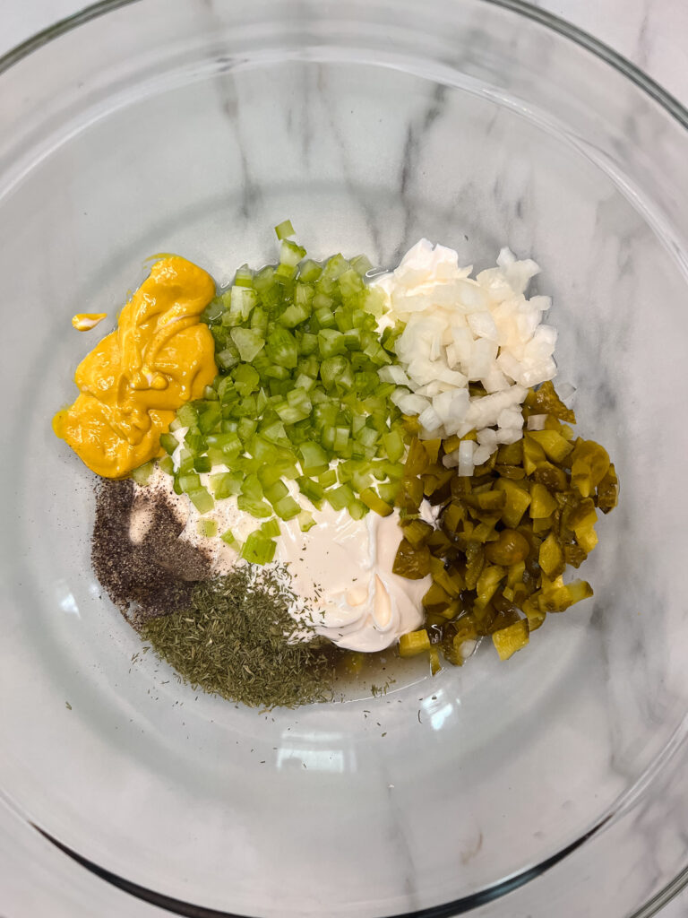 vegan potato salad ingredients in a a glass bowl. 