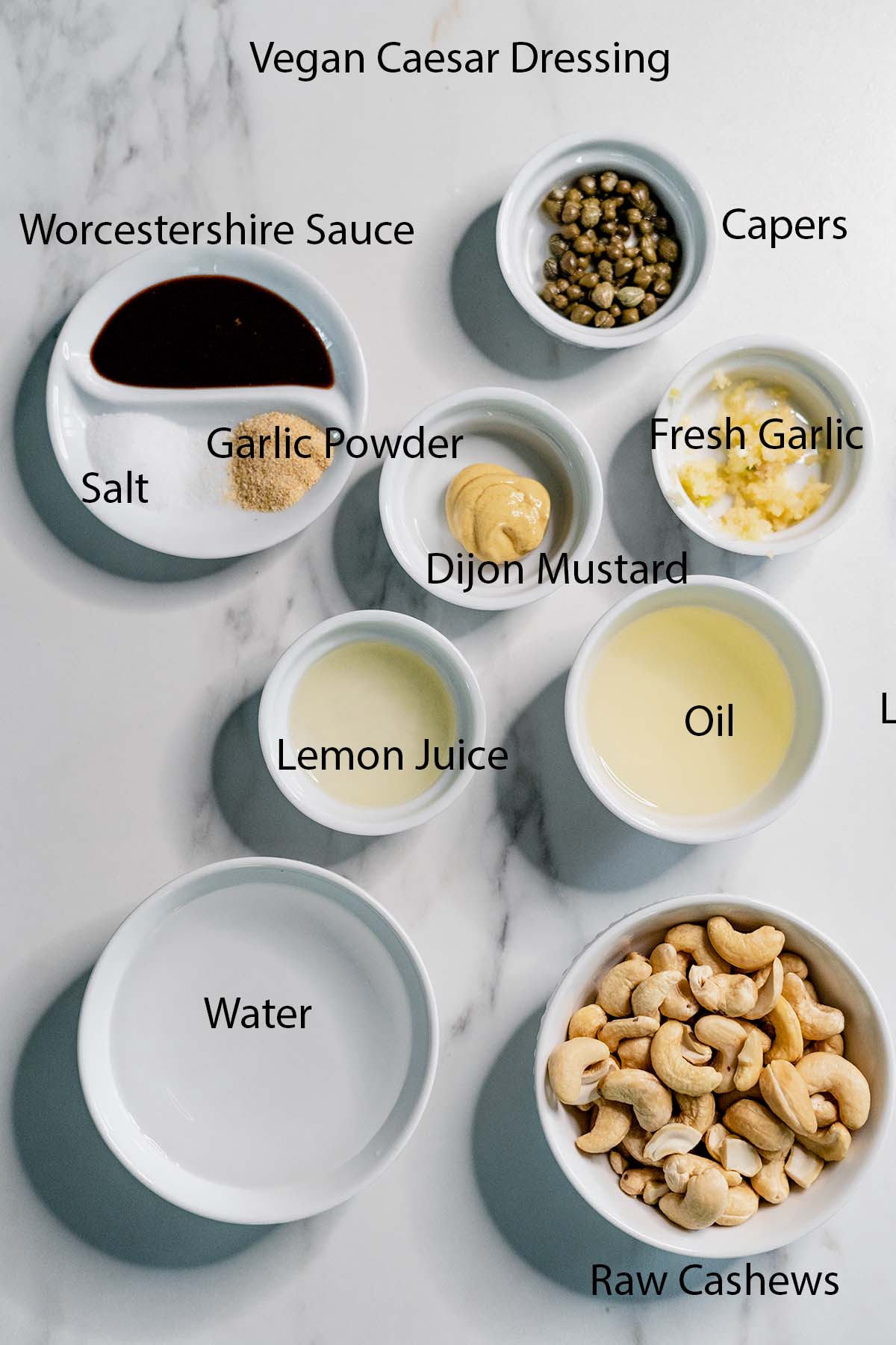 Vegan Caesar Dressing ingredients in small bowls with black labels on it. 