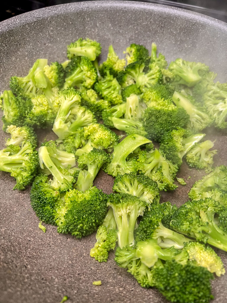 Broccoli steaming on a black skillet. 