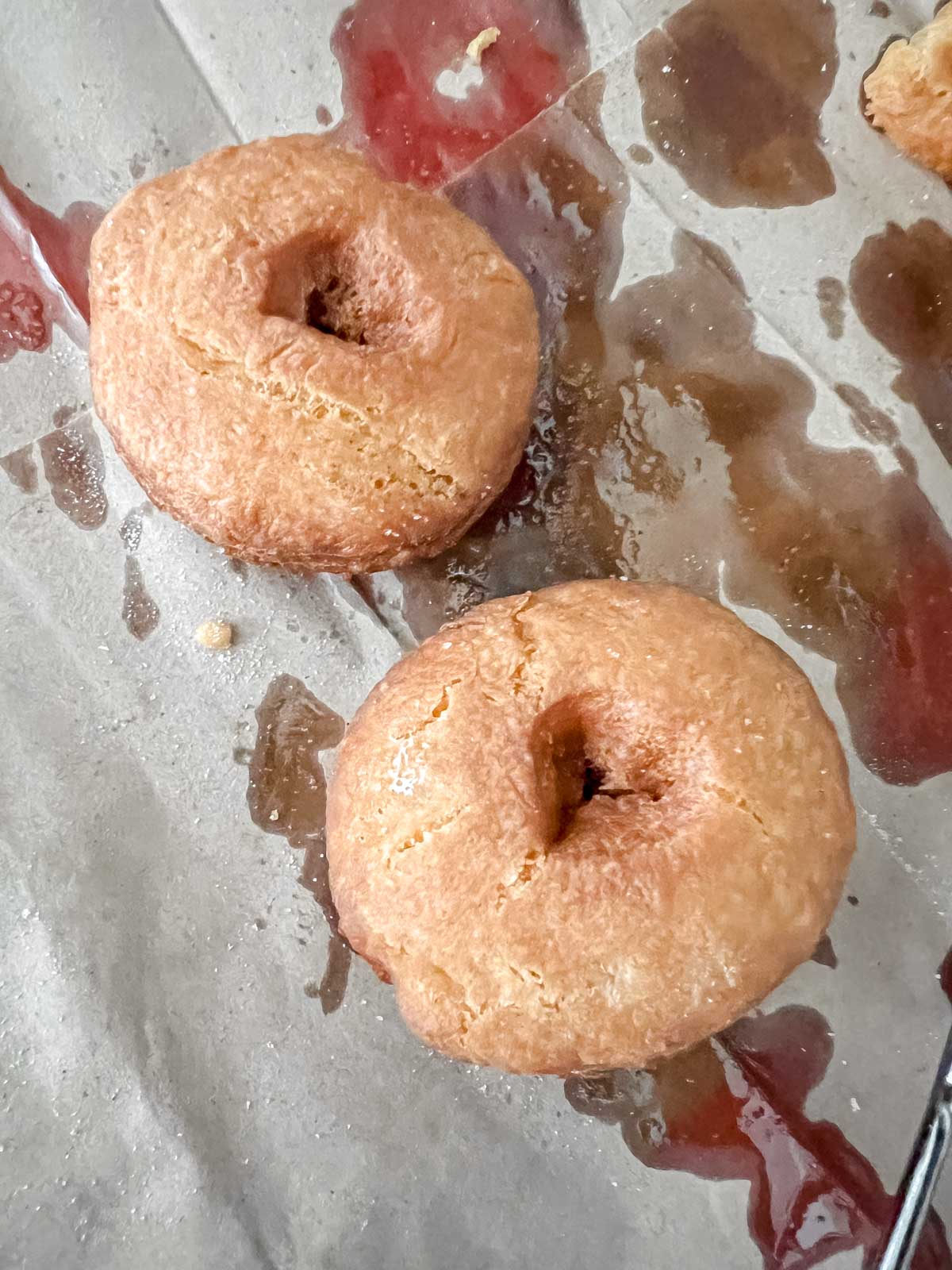 Two vegan apple cider donuts after frying on a brown paper bag. 