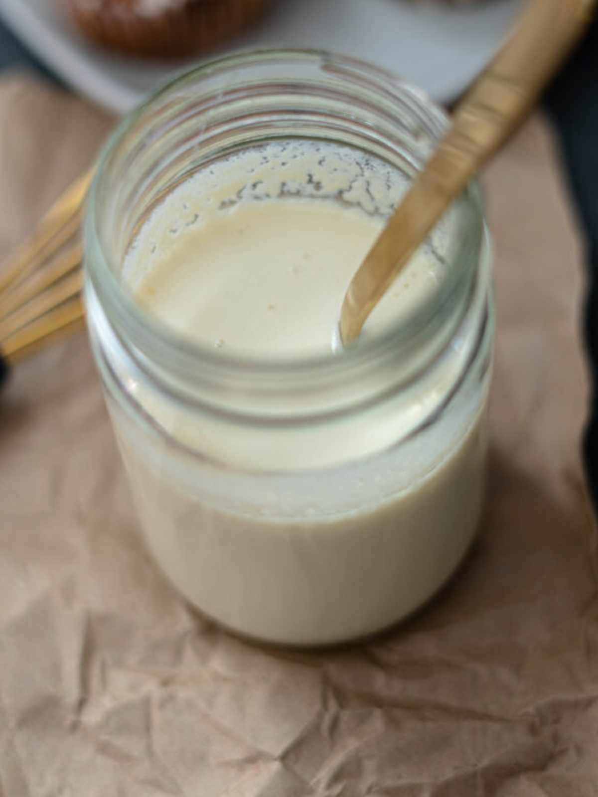 Vegan buttermilk in a glass mason jar with a gold spoon in it.