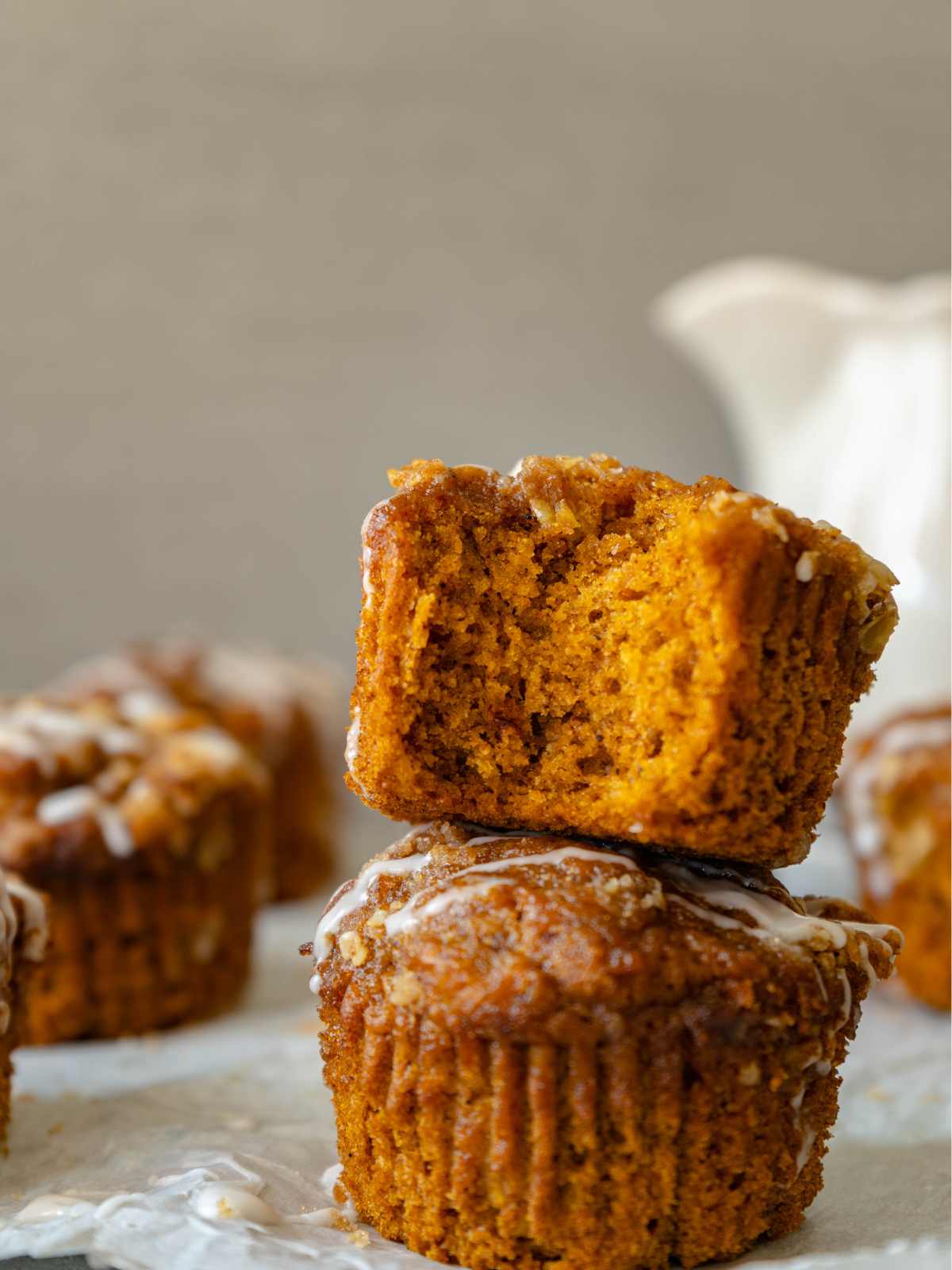 Vegan pumpkin muffins stacked two high with a bite out of it. 