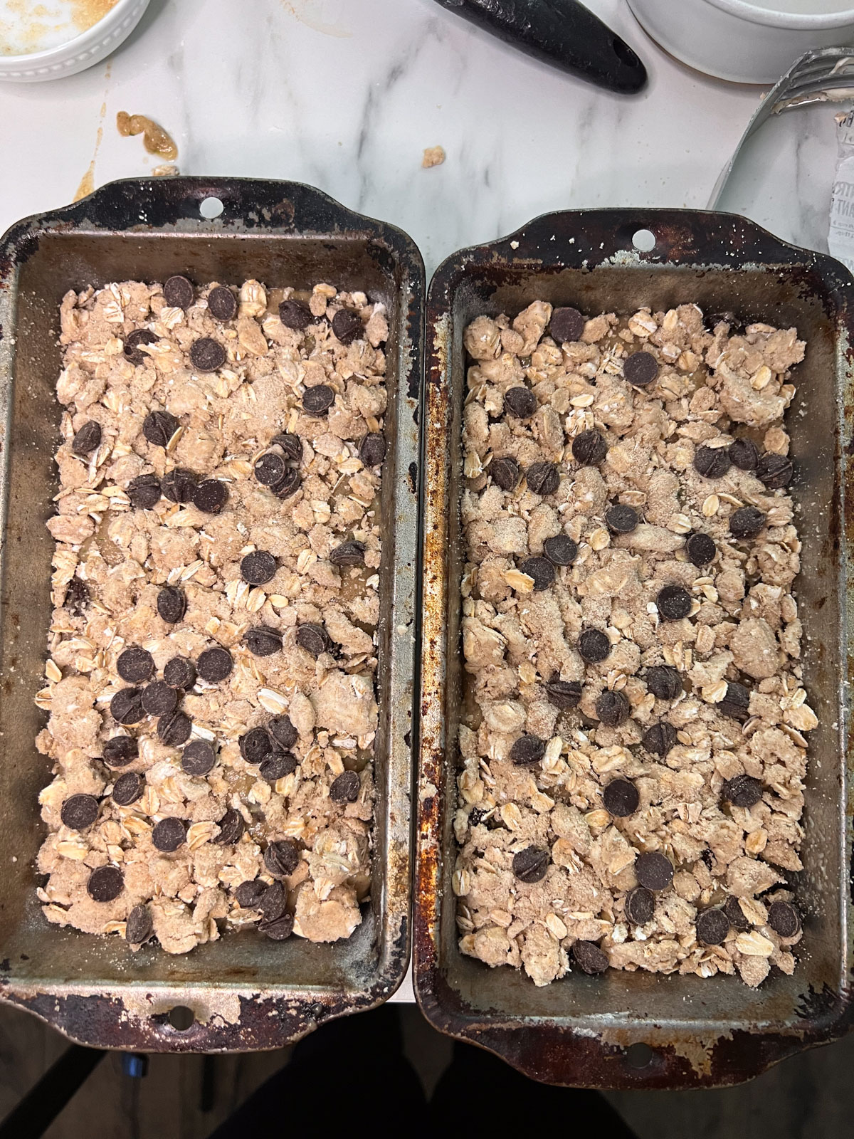 Prebaked vegan zucchini bread with streusel topping side by side in their tin. 