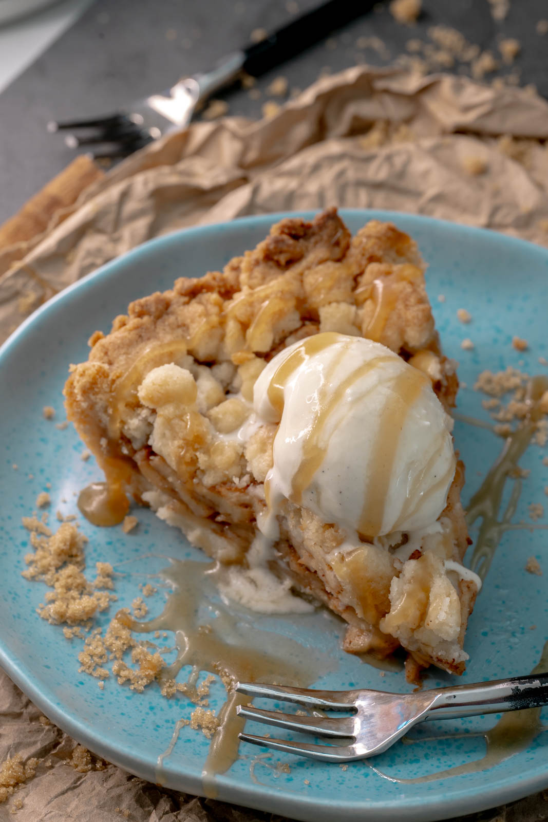 A overhead shot of the vegan apple pie with a slice of ice cream and caramel on a small blue plate. 