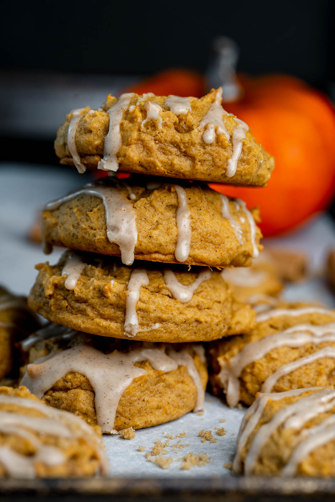 Vegan pumpkin cookie stacked 4 high with glaze dripping from them. 