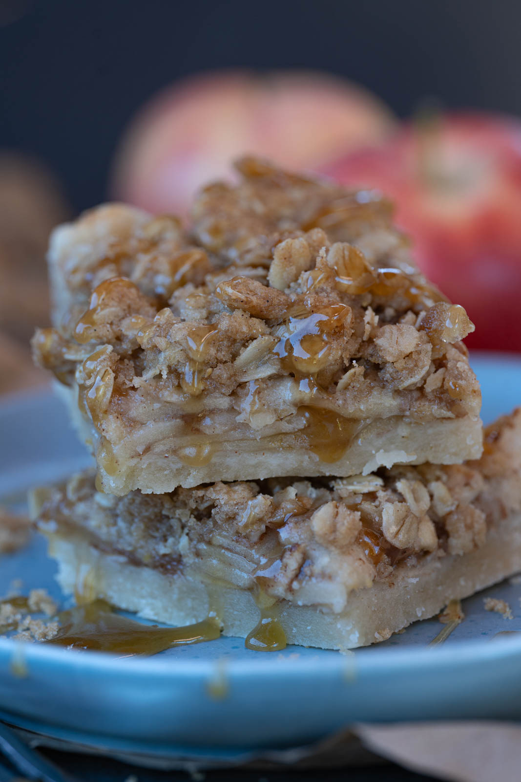 Two vegan apple pie bars stacked on top of each other- close up shot with vegan caramel dripping down. 