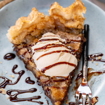 vegan chocolate chip pie on a small plate with a scoop of vegan ice cream and drizzle of chocolate sauce.