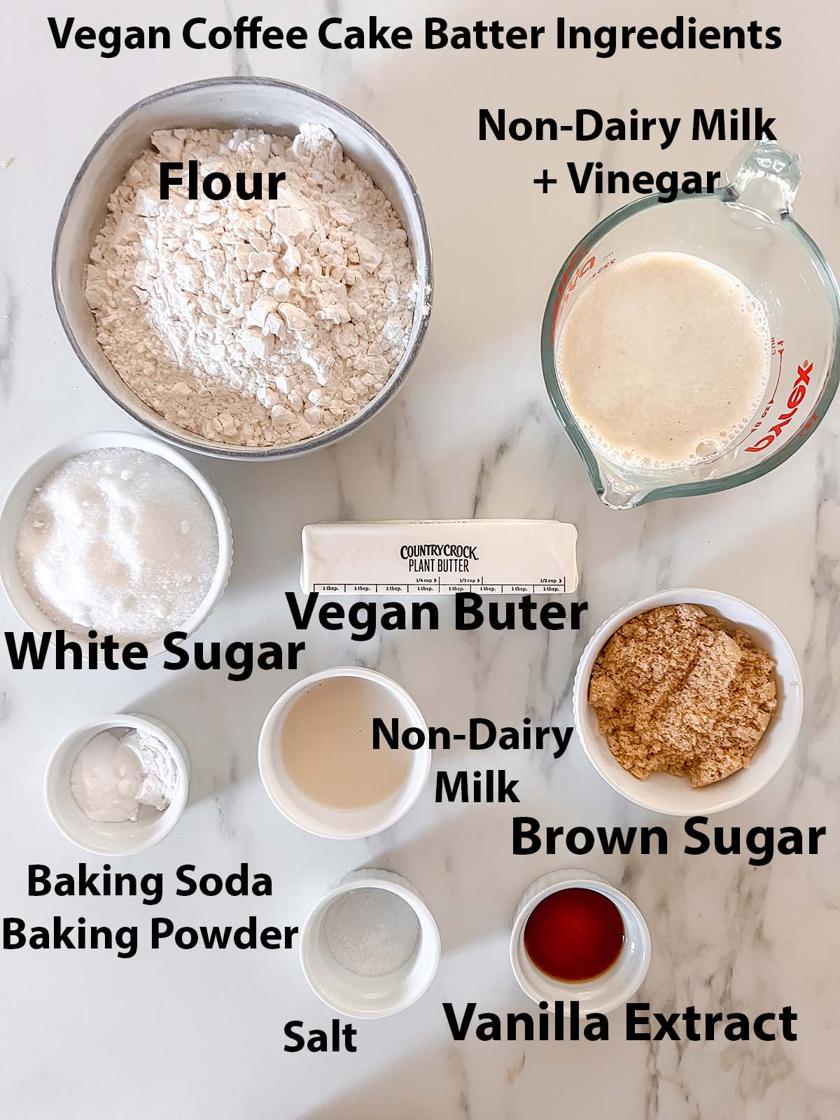 All the ingredients for vegan coffee cake batter in small bowls with black writing for labels. 
