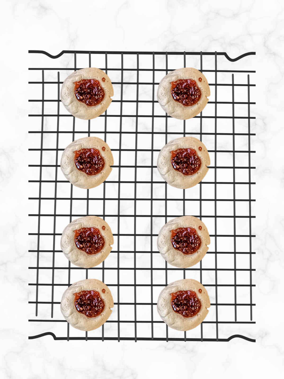 Vegan thumbprint cookies on a cooling rack with jam on them. 