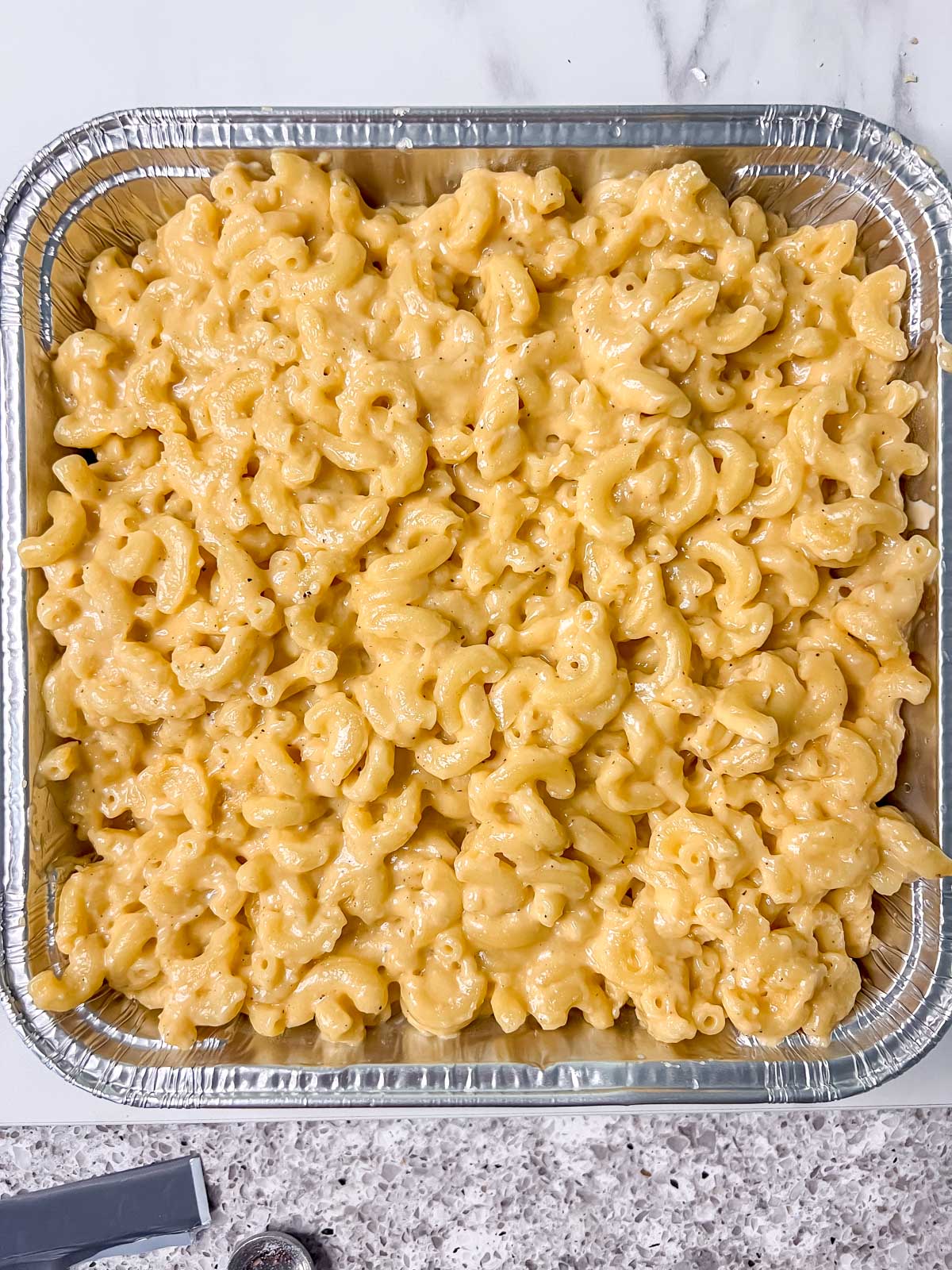 A silver tin with vegan mac and mac and cheese before getting baked. 