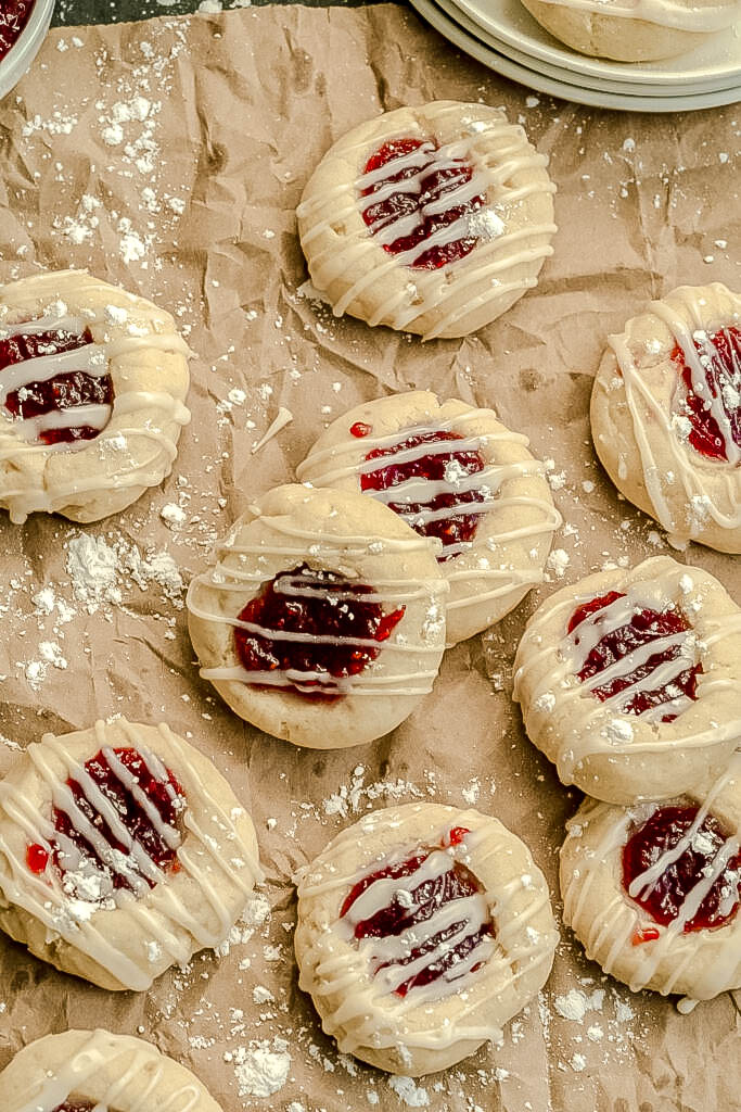 Vegan thumbprint cookies on a brown paper bag staked and scattered. 