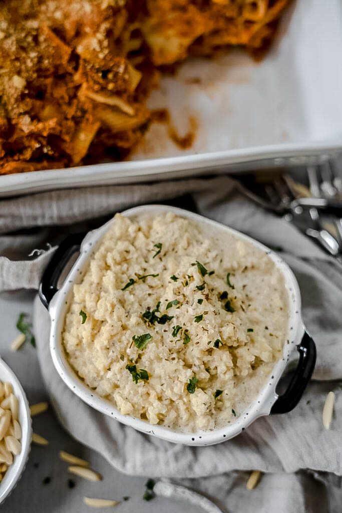 Vegan ricotta cheese in a small container on a grey background. 